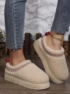 Vue détaillée de bottes de neige plateforme en laine d'agneau crème avec motifs tissés rouges.