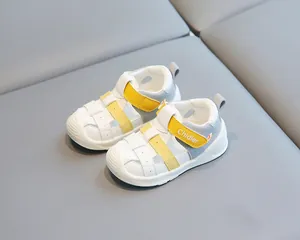 Gros plan de sandales en cuir blanc et jaune pour tout-petits, semelle souple.