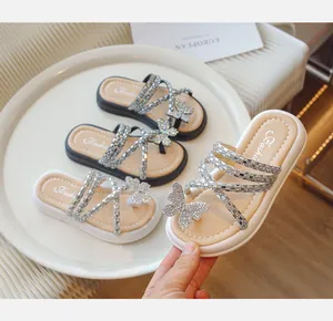 Primer plano de chanclas para niñas con pedrería, detalle mariposa y tiras brillantes