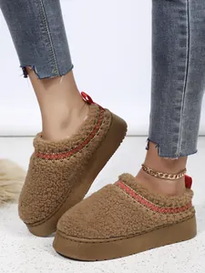 Gros plan de bottines de neige à plateforme en sherpa marron pour femme avec surpiqûres.
