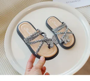 Vista detallada de sandalias de princesa para niña con mariposa de pedrería en negro y beige.