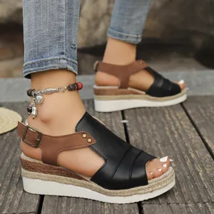 Detail of women's black and brown wedge sandals with espadrille soles on a wooden deck.