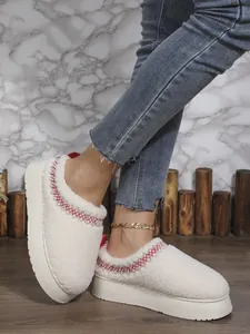 Gros plan sur des bottes de neige à plateforme en polaire crème avec broderie rouge décorative