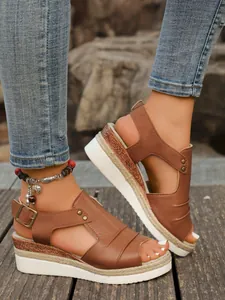 Detail view of brown peep-toe wedge sandals with jute rope sole on a wooden surface