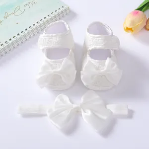 Detailansicht der weißen Baby-Prinzessin-Schuhe aus Spitze mit passendem Stirnband