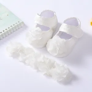 Detailansicht von weißen Spitzen-Babyschuhen und passendem Blumen-Stirnband für Babys