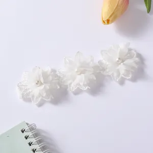 Detailansicht weißer Spitzenblumen mit Perlen auf einem elastischen Baby-Stirnband