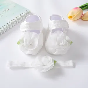 Detailansicht weißer Babyschuhe aus Spitze mit Blume und passendem Stirnband-Set