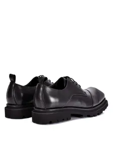 Gedetailleerd achteraanzicht van zwarte heren Derby schoenen van echt leer met dikke zool