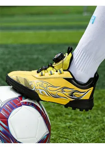 Detailed view of yellow children's soccer cleats with flame design and rotating dial lacing