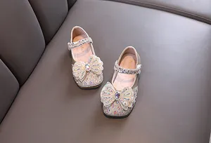 Vista detallada de zapatos de princesa dorados para niñas con lazos de pedrería