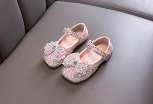 Vista detallada de los zapatos Mary Jane rosas para niñas con lazos de pedrería brillantes.