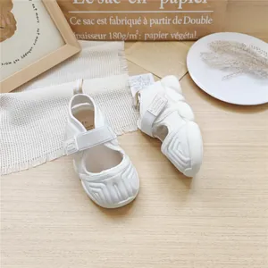 Macro view of white toddler sport sandals on a minimalist wooden table