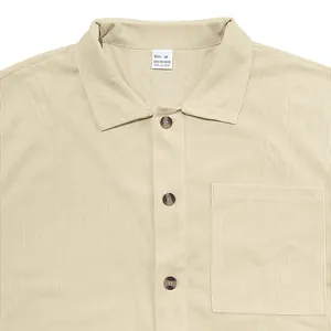 Dettaglio di camicia beige da uomo con colletto a rever, bottoni e taschino frontale