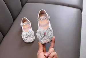 Vista detallada de zapatos de princesa blancos para niña con brillantes pedrería y un lazo.