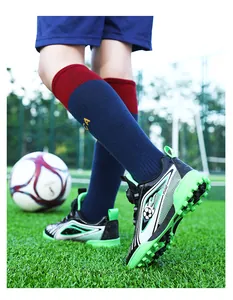 Dettaglio ravvicinato scarpe calcio professionali nere e verdi per bambini su erba