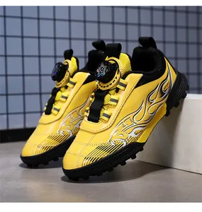Detail of yellow kids' turf soccer shoes with flame pattern and dial lacing system.
