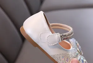 Primer plano de zapatos de princesa blancos para niña con pedrería brillante y elegante