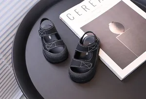 Dettaglio macro di sandali neri per bambini con design a punta chiusa e cuciture bianche