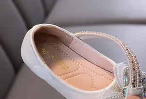 Detalle de zapato de princesa blanco para niña con pedrería y forro interior suave