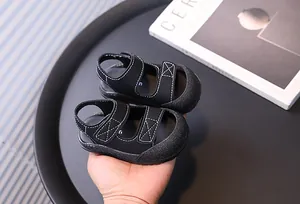 Dettaglio di sandali neri per neonati con cuciture bianche e chiusura in velcro