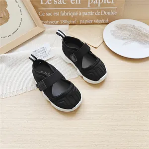 Side view of black children's sports sandals on a minimalist wooden background