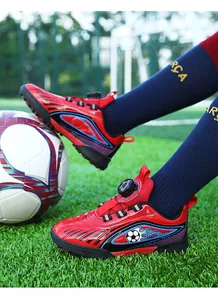 Primo piano di scarpe da calcio rosse per bambini con chiusura a rotella su erba sintetica