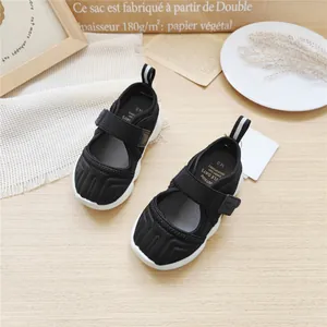 Detailed view of children's black sport sandals interior and velcro strap on wooden desk