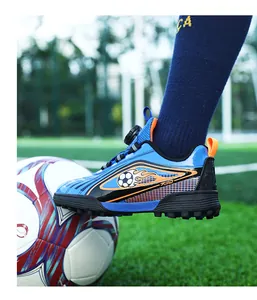 Foto d'azione di scarpa da calcio blu per bambini su pallone in campo in erba