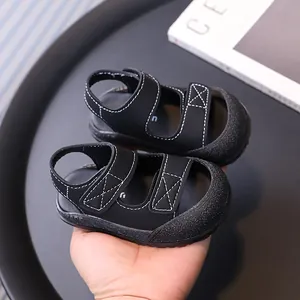 Sandali neri chiusi per neonati con suola morbida e cuciture bianche per bambini piccoli.
