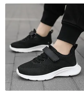 Vista lateral detallada de zapatillas deportivas negras de malla transpirable para las niñas.