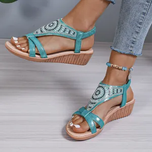 Detail view of bohemian turquoise rhinestone wedge sandals worn on feet.