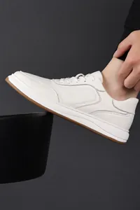 Detailed side view of white genuine leather men's sneakers with premium texture