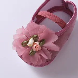 Close-up detail of pink baby princess shoe featuring a large mesh flower and ribbon roses