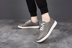 Detail view of grey breathable cowhide leather casual sneakers with white laces for men.