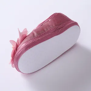 Macro shot of the white dotted anti-slip sole on a pink soft-sole baby princess shoe.
