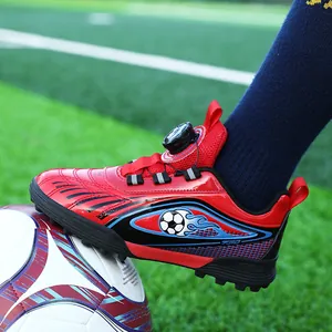 Scarpe da calcio rosse per bambini con fibbia rotante su campo d'erba
