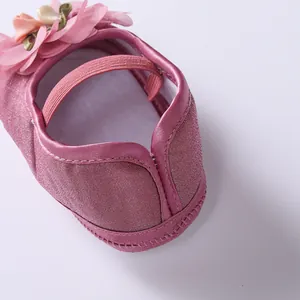 Close-up detail of the elastic strap and soft heel of a pink baby princess dress shoe.
