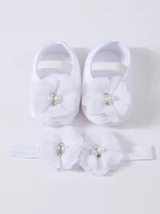 Vue détaillée de chaussures de princesse blanches pour bébé avec bandeau assorti.