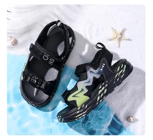 Nahaufnahme der schwarzen Jungen-Sommersandalen mit rutschfester Sohle am Strand