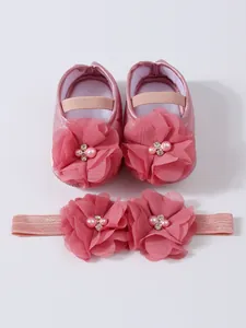 Gros plan de chaussures de princesse rose pour bébé et coffret bandeau floral assorti