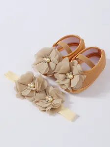Vue détaillée exquise des chaussures de princesse bébé champagne et du bandeau assorti