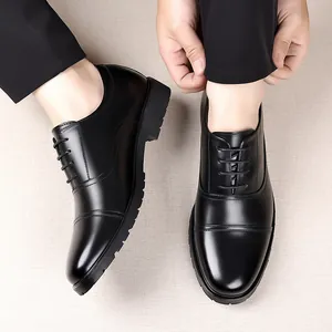 Close-up of men's black leather cap-toe dress shoes worn with formal black trousers.