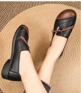 Close-up of breathable hollow-out leather shoes for elderly women on a woven mat.