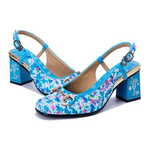 Detalle de sandalias destalonadas de pelo de potro con flores azules y hebilla dorada