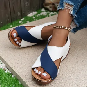 Detailed view of blue and white wedge sandals with open-toe design on outdoor stone