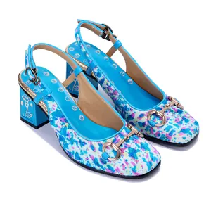Detalle de sandalias de tacón grueso con estampado floral y hebilla dorada.