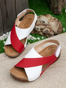 Top view of stylish red and white platform Roman sandals in a natural outdoor setting