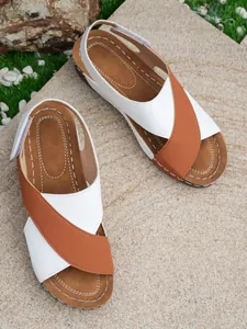 Detail view of women's Roman wedge sandals with white and brown cross-strap design