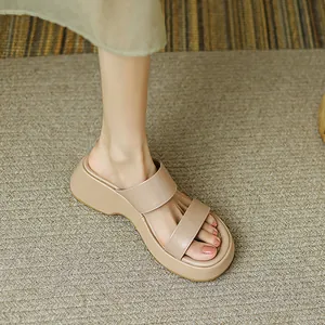 Primer plano de sandalias beige con plataforma y doble tira sobre alfombra